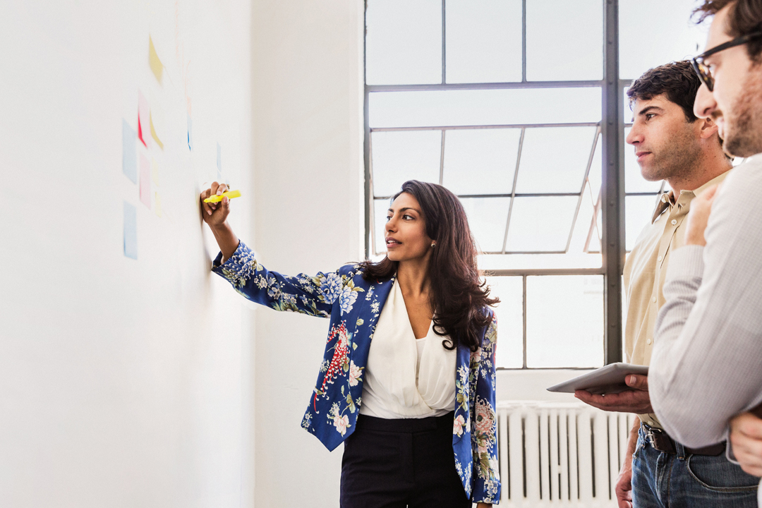 Woman standing at white board writing in meeting